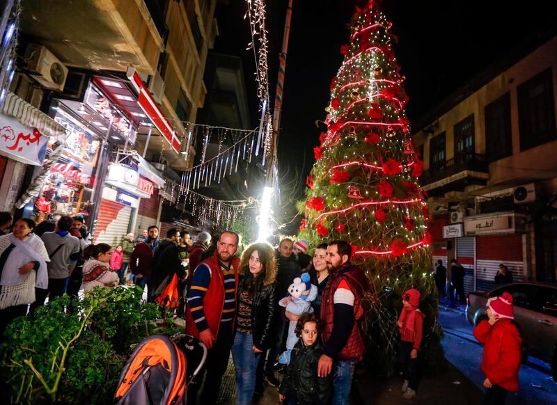 Syrians pose for a picture as they gather around a Christmas tree in the central neighbourhood of Qassaa, Damascus. AFP