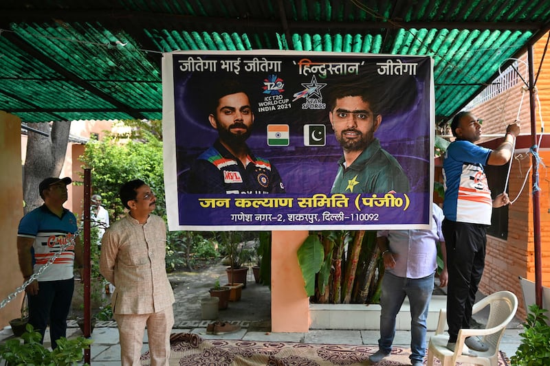 Cricket fans in New Delshi tie a banner with the pictures of India's captain Virat Kohli (L) and Pakistan's captain Babar Azam (R). AFP
