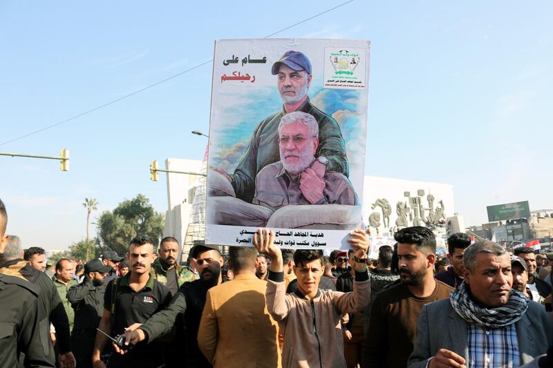 epa08916771 A Supporter of Iran-backed Iraqi Shiite Popular Mobilization Forces holds the picture of Qasem Soleimani and Iraqi militia commander Abu Mahdi al-Muhandis during a demonstration on the first anniversary of a US drone attack that killed the Iranian general Qasem Soleimani and Abu Mahdi al-Muhandis, the deputy leader of the Popular Mobilization Forces militia at the main road of Baghdad international Airport in Baghdad, Iraq, 03 January 2021. Thousands of the Supporters of Iraqi Shiite Popular Mobilization Forces gathered at the al-Tahrir square in central Baghdad, on the first anniversary of the killing of Iraqi militia commander Abu Mahdi al-Muhandis and Qasem Soleimani, the head of Iran's Islamic Revolutionary Guard Corps' elite Quds Force, and the eight others at the Baghdad international airport on 03 January 2020. The deonstrators called for the withdrawal of US forces from Iraq.  EPA/AHMED JALIL