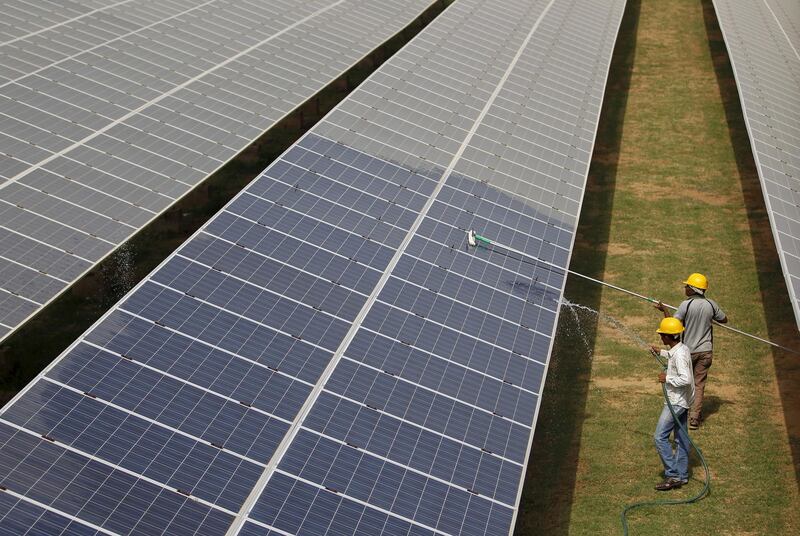 FILE PHOTO: Workers clean photovoltaic panels inside a solar power plant in Gujarat, India, July 2, 2015. REUTERS/Amit Dave/File Photo