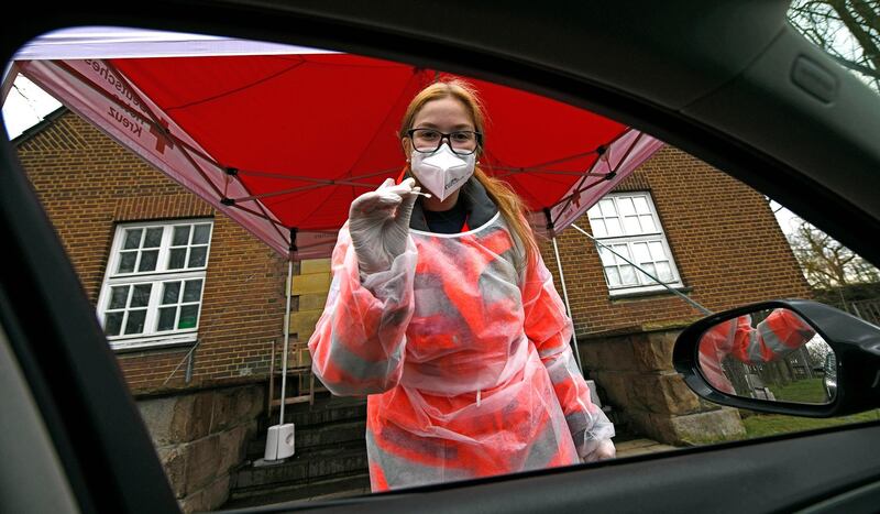 A Red Cross worker in protective clothes prepares to administer a COVID-19 rapid test at a coronavirus test drive-in in Gelsenkirchen, Germany, Wednesday, March 17, 2021. The German federal government offers one free rapid test per week for every citizen. (AP Photo/Martin Meissner)