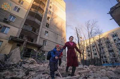 A woman with a child evacuates from a residential building damaged by shelling, in Kyiv, Ukraine. Reuters
