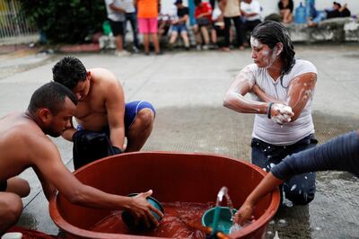 Migrants, part of a caravan traveling from Central America en route to the United States, clean themselves and wash their clothes in the street in Metapa, Mexico November 3, 2018. REUTERS/Carlos Garcia Rawlins