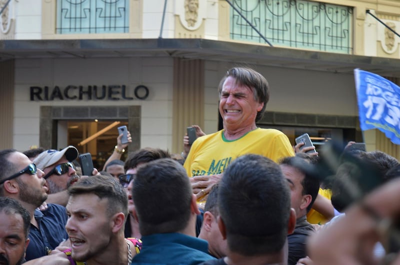 Presidential candidate Jair Bolsonaro grimaces right after being stabbed in the stomach during a campaign rally in Juiz de Fora, Brazil, Thursday, Sept. 6, 2018. Bolsonaro, a leading presidential candidate in Brazil, was stabbed during a campaign event, though officials and his son said the injury is not life-threatening. (AP Photo/Raysa Leite)