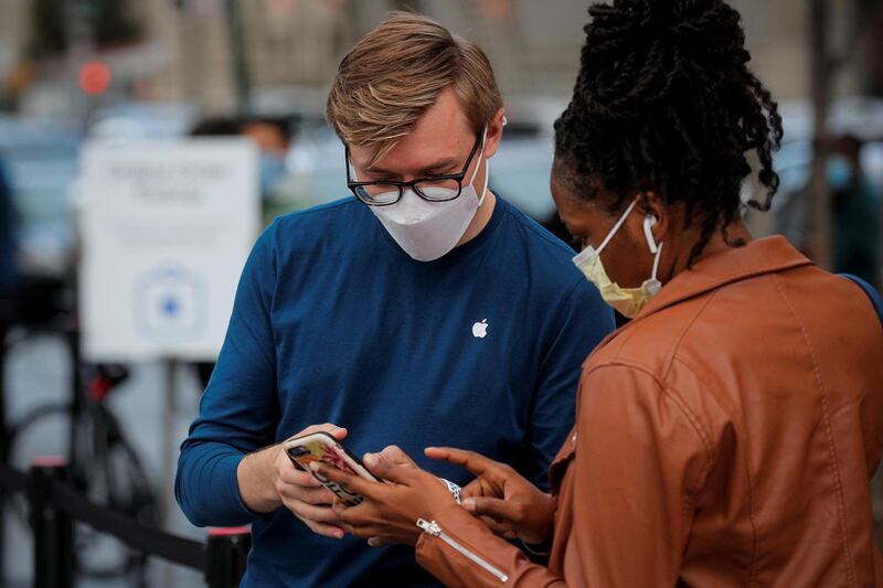 A customer speaks to an employee outside an Apple Store to pick up the new 5G iPhone 12, as the coronavirus disease (Covid-19) outbreak continues in Brooklyn, New York, U.S. Reuters