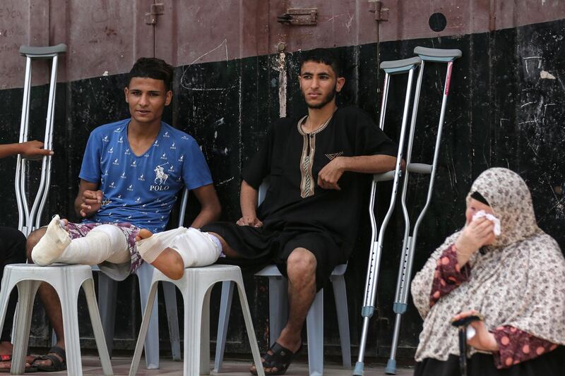 Wounded Palestinian men sit attend the funeral of Moein Al-Saai, who died of wounds he sustained protesting at the Israeli-Gaza border, during his funeral in Gaza city on May 19, 2018. Moein Al-Saai, aged 51, was shot by Israeli forces on May 14, when 60 Palestinians were killed and thousands injured in a single day of protests that coincided with Monday's move of the US embassy from Tel Aviv to Jerusalem. / AFP / MAHMUD HAMS
