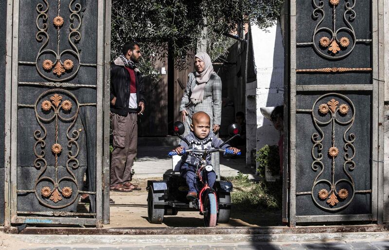 Zain, 5, a Palestinian boy with a disability, rides an electric vehicle assembled by Abu Raida, who is seen in the background, in Bani Suhaila. AFP