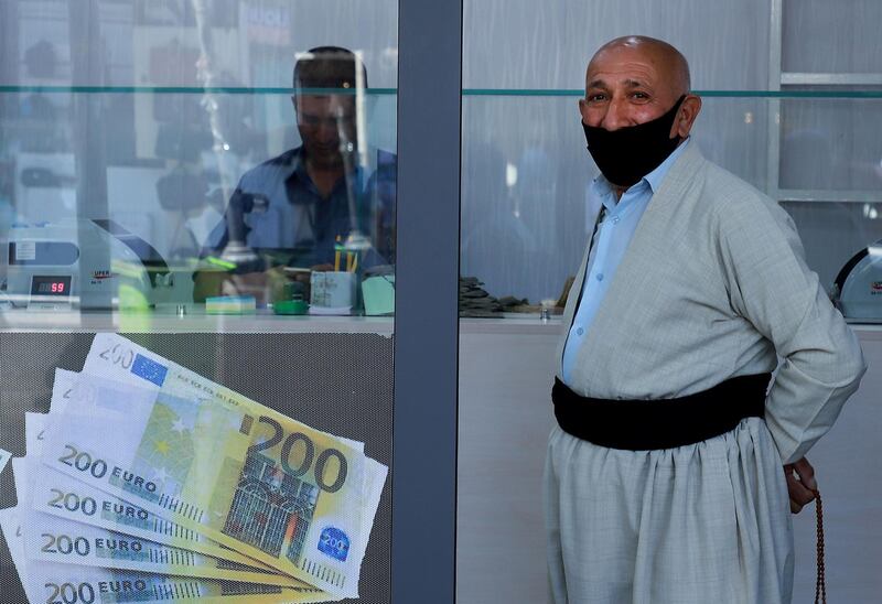 An Iraqi man, wearing a protective mask waits at a money exchange office in Sulaimaniyah city. AFP
