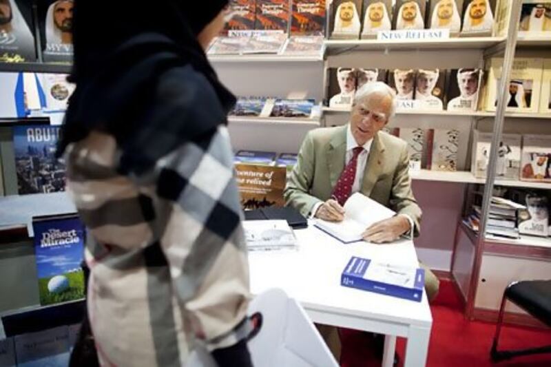 Author David Heard of the UK signs a copy of his book, From Pearls to Oil, during the Abu Dhabi International Book Fair. Christopher Pike / The National