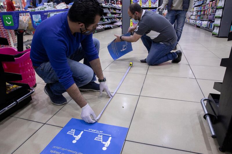 Staff members put in place stickers showing distancing measures to be respected by customers, at a supermarket, in Amman, Jordan.  EPA