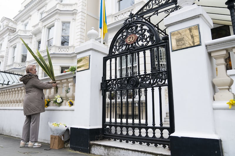 A woman lays a tribute outside the Ukrainian Embassy, in London. PA