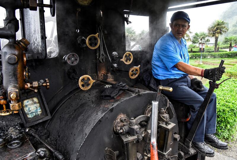 Train driver Hari Chettri sits in the engine of Darjeeling Himalayan Railway steam train as it leaves Batasia Loop.