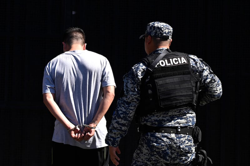 A man detained over alleged gang links is escorted by an officer of the National Civil Police at the San Salvador penal centre. AFP