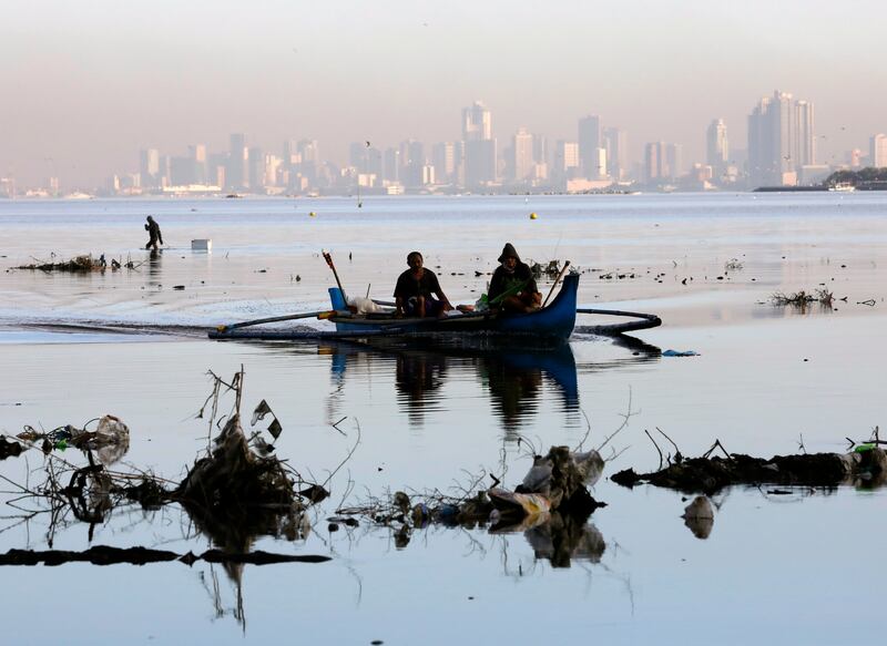 Fishermen steer a boat through debris off the shore of Manila, Philippines. The archipelago is surrounded by vast body of water, but finding potable sources is a challenge for many. EPA