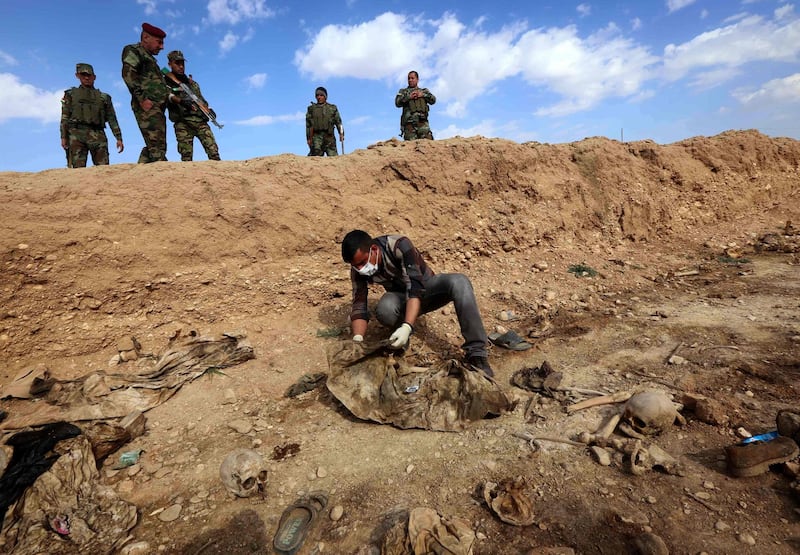 (FILES) In this file photo taken on February 03, 2015 An Iraqi man inspects, the remains of members of the Yazidi minority killed by the Islamic State (IS) jihadist group after Kurdish forces discovered a mass grave near the village of Sinuni, in the northwestern Sinjar area.  The Islamic State group left behind more than 200 mass graves in Iraq containing up to 12,000 victims that could hold vital evidence of war crimes, the UN said November 6, 2018.
The United Nations in Iraq (UNAMI) and its human rights office said they had documented a total of 202 mass graves in parts of western and northern Iraq held by IS between 2014 and 2017. / AFP / Safin HAMED AND Safin HAMED
