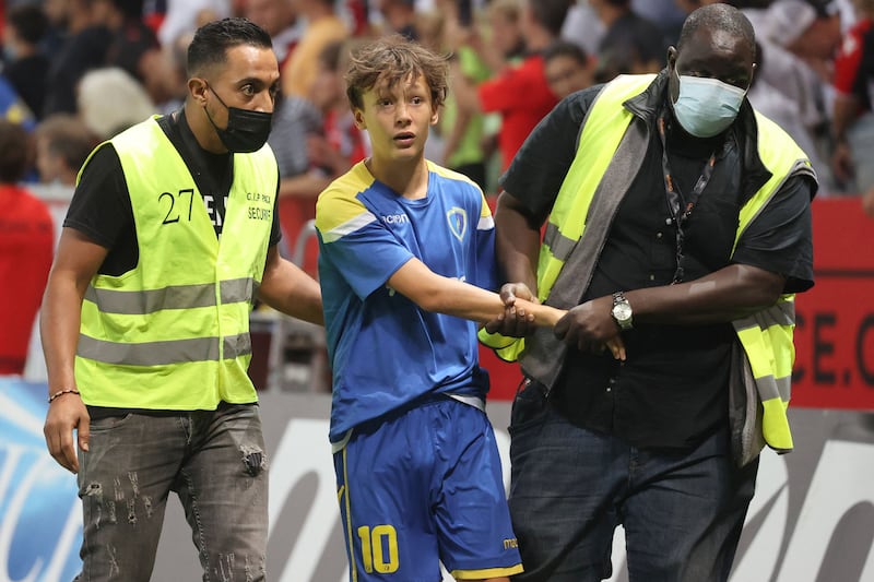 Security detain a fan as others try to invade the pitch. AFP