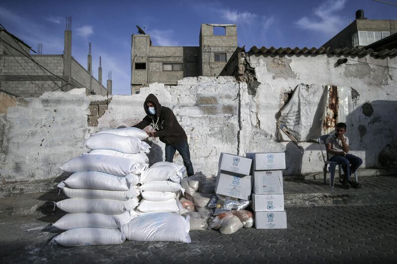 A Palestinian man wearing a protective mask sorts food aid provided by the United Nations Relief and Works Agency for Palestinian Refugees (UNRWA), to be delivered to refugee homes at the al-Shati camp, in Gaza city instead of the usual distribution at a UN centre in the city, due to the Covid-19 pandemic.  AFP