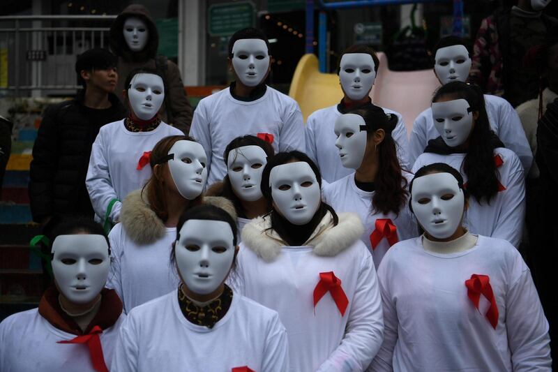 Volunteers wearing white masks and red ribbons on their shirts take part in an event to raise awareness on HIV in Chongqing, China. CNS / Reuters