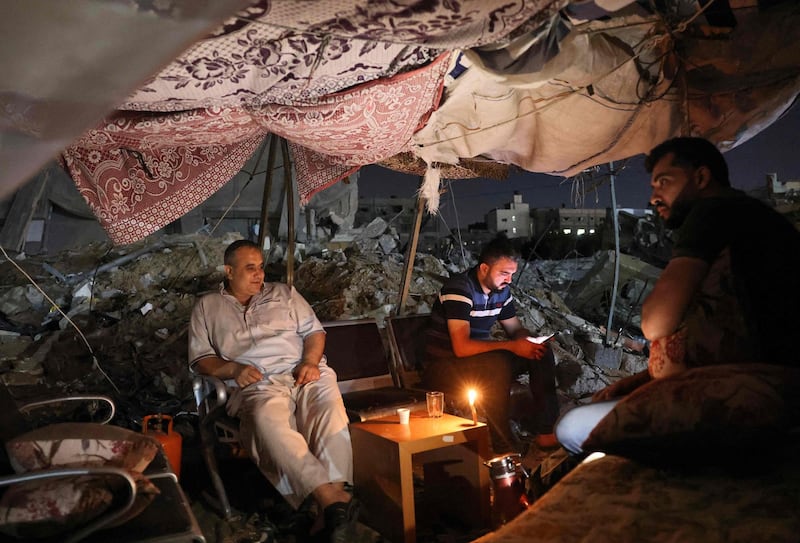 Palestinians sit in a tent that has been set up on top of the ruins of a building destroyed in recent Israeli air strikes, in Gaza city. AFP