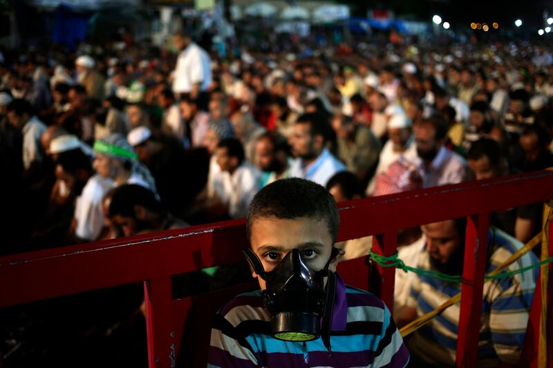 A boy wears a tear gas mask as supporters of Egypt's ousted President Mohammed Morsi pray at Nasr City, where protesters have installed a camp and hold daily rallies, in Cairo, Egypt, Sunday, July 28, 2013. Deadly clashes broke out during funerals of slain supporters of Egypt's ousted Islamist president Sunday, as the supreme leader of the Muslim Brotherhood urged his followers to stand fast after more than 80 of them were killed in weekend violence. (AP Photo/Hassan Ammar) *** Local Caption ***  APTOPIX Mideast Egypt.JPEG-00da9.jpg