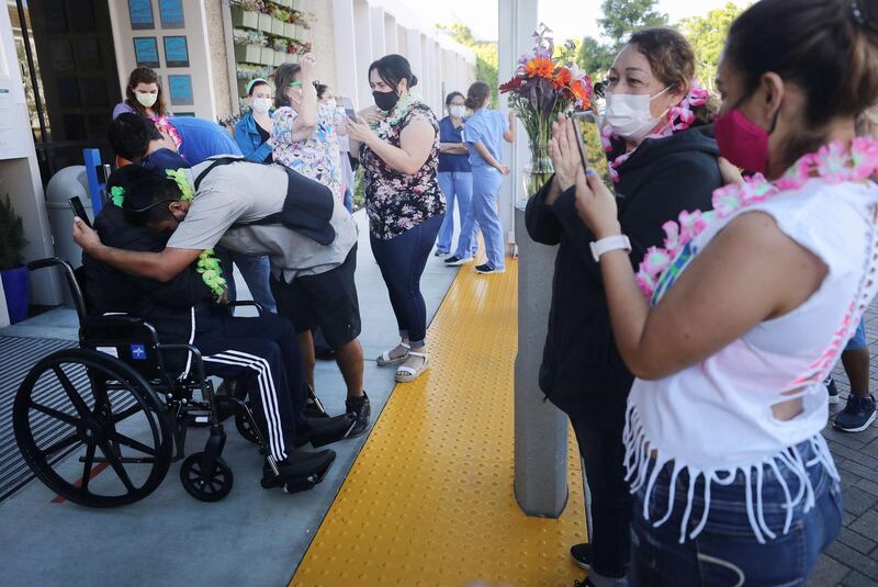 Isaias Perez Yanez, 59, in wheelchair, is hugged and applauded by family and hospital staff as he is released from Sharp Coronado Hospital in Coronado, California. Getty Images/AFP