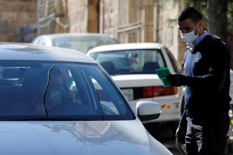 A policeman checks the identity card of a Palestinian entering to the city of Bethlehem amid coronavirus precautions, in the Israeli-occupied West Bank. Reuters