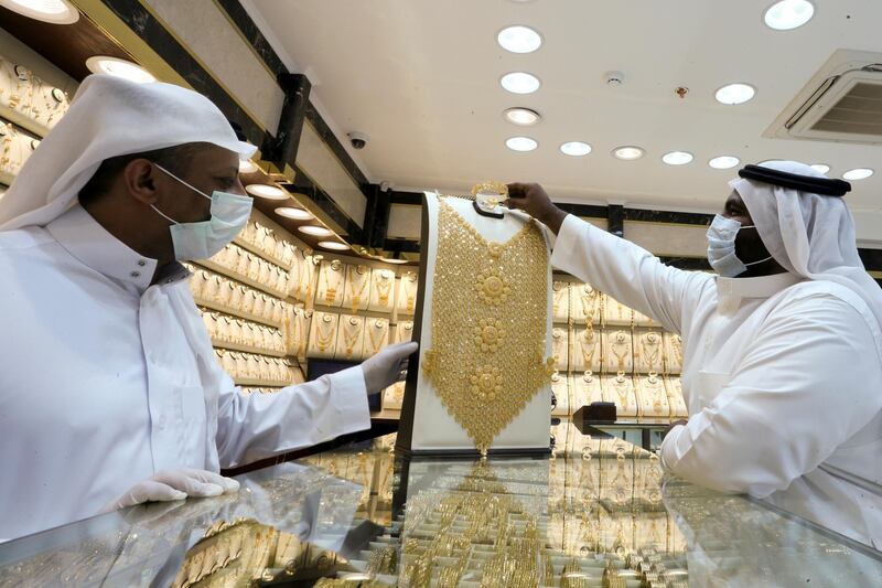 A Saudi jeweller wearing a protective face mask displays a gold necklace to a customer in Riyadh. Reuters