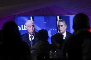 People watch a televised debate between presidential candidates Kais Saied, left, and Nabil Karoui, on the last day of campaigning before the second round of the presidential elections, in Tunis, Tunisia, Friday, October 11, 2019. AP