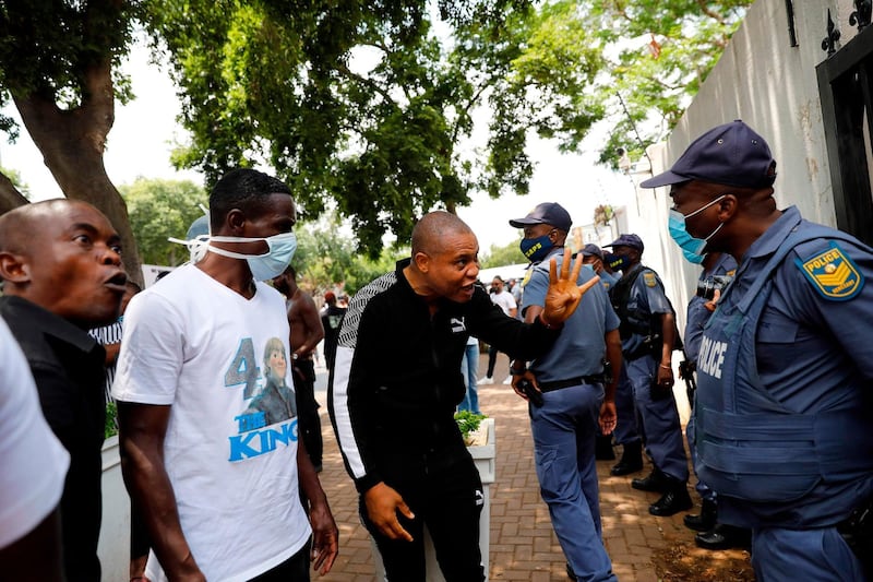 Nigerians based in South Africa react to South African Police Service (SAPS) officers as they protest outside the Nigerian embassy in Pretoria.  AFP
