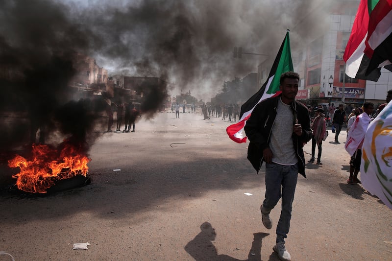 Protesters in Khartoum set tyres alight, filling the air with black smoke. AP