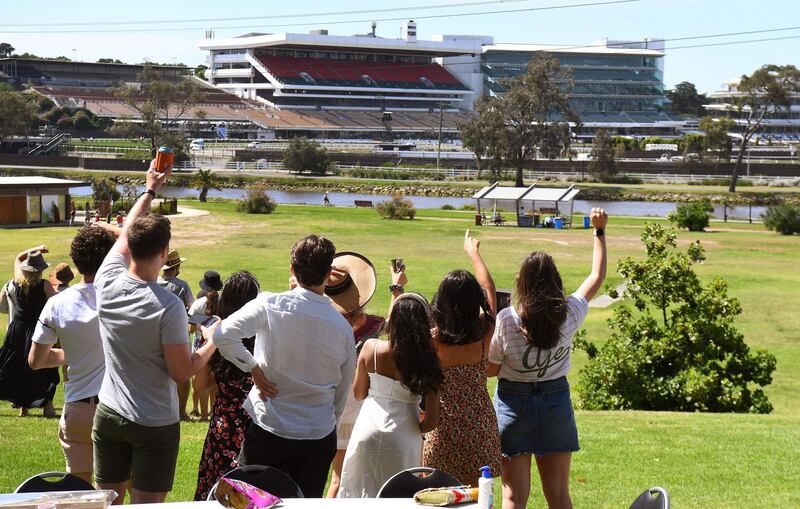 Punters watch the spectator-free Melbourne Cup horse race from a distance as they picnic in a park overlooking the Flemington Racecourse in Melbourne. AFP