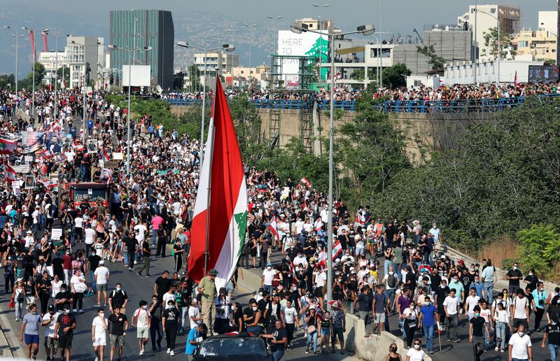 People carry flags and banners as they march to mark the anniversary of Beirut's port blast.