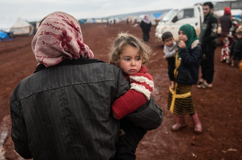 A displaced Syrian woman carries her baby at Marabune camp in Idlib, Syria. Getty Images