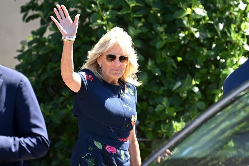 First Lady Jill Biden pairs her blue patterned Oscar de la Renta midi-dress with tan sunglasses. AP