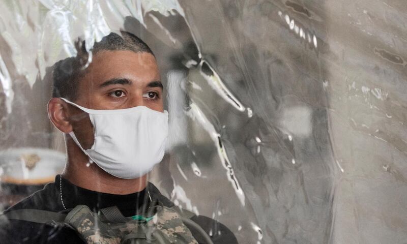 A cadet candidate stands behind a plastic screen as he gets instructions on his arrival at the U.S. Military Academy, in West Point, N.Y. The Army is welcoming more than 1,200 candidates from every state. Candidates will be COVID-19 tested immediately upon arrival, wear masks, and practice social distancing. AP Photo
