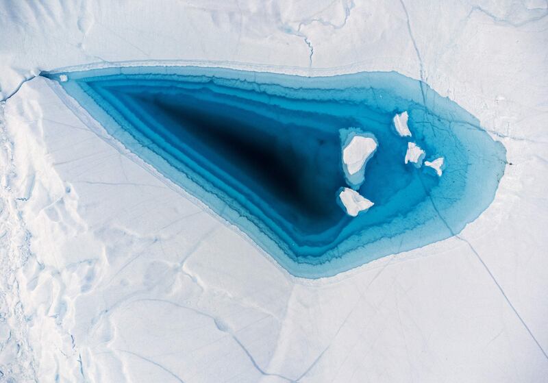 Turquoise water gathers in a large melt hole at the top of an iceberg in the Disko bay, western Greenland. The iceberg originates from the Jakobshavn glacier, the most productive in the Northern Hemisphere. The massive icebergs that detach from the glacier float for years in the waters in front of the fjord before being carried south by ocean currents.  AFP