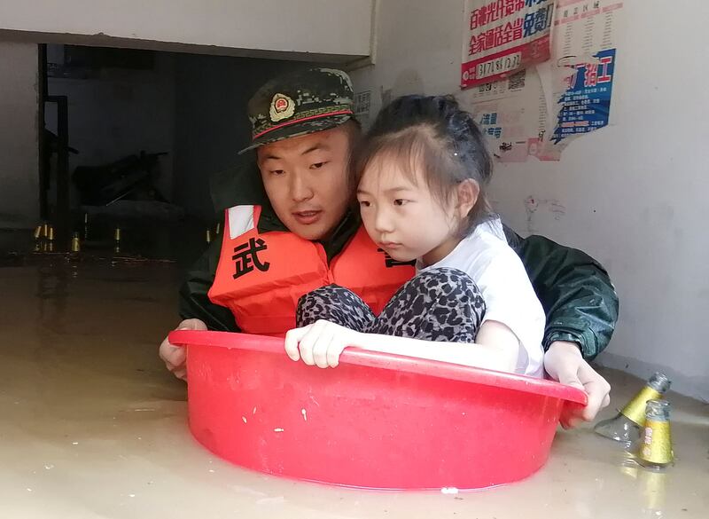 This photo taken on August 12, 2021 shows a paramilitary police officer evacuating a child from a flooded area following heavy rains in Suizhou, in China's central Hubei province.  (Photo by -  /  CNS  /  AFP)  /  China OUT