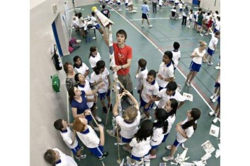 Readers of tomorrow: Matthew Kilsby, a senior, instals the last part of his team's newspaper tower during a contest in the induction sessions at Dubai College. His team's was the second-highest tower. Jeff Topping / The National