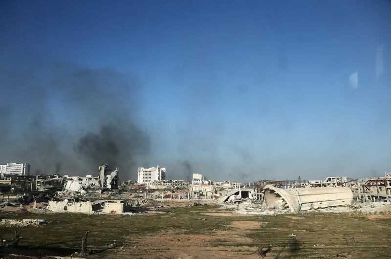 A photo taken from a bus in a convoy transporting Syrian civilians and rebel fighters shows smoke rising from destroyed buildings in Arbin in Eastern Ghouta as they are evacuated from the opposition enclave to the village of Qalaat al-Madiq, some 45 kilometres northwest of the central city of Hama, on March 25, 2018. Abdulmonam Eassa / AFP