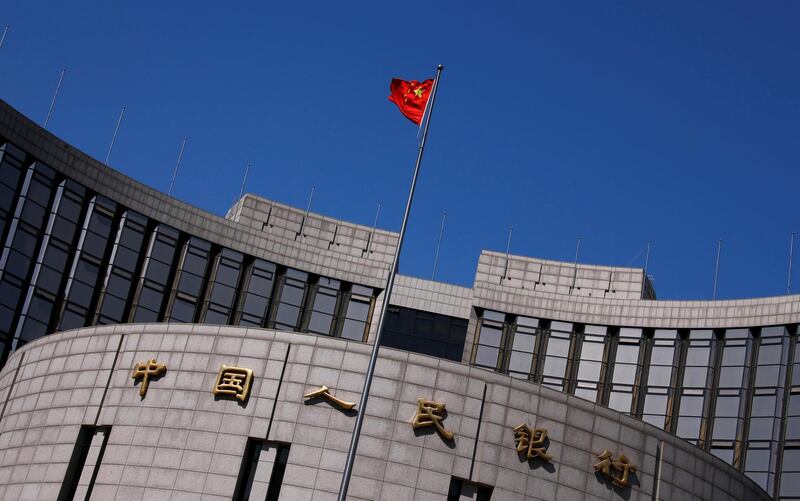 FILE PHOTO: A Chinese national flag flutters outside the headquarters of the People's Bank of China, the Chinese central bank, in Beijing, China April 3, 2014. B REUTERS/Petar Kujundzic/File Photo