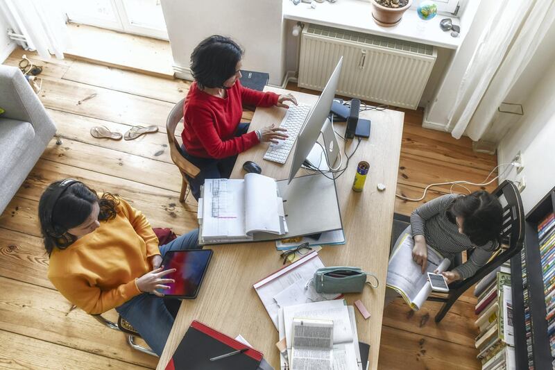 overhead view on woman working at home in living room, daughters doing home work