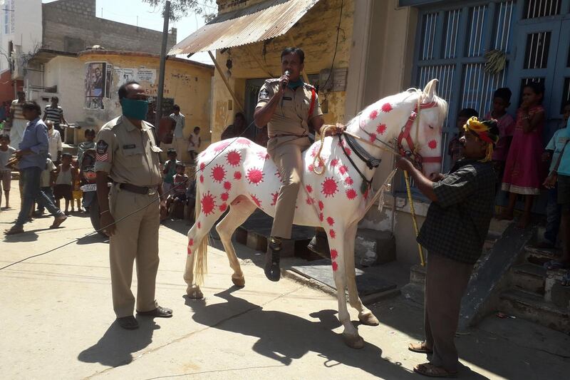 A police officer (C) rides a horse covered with coronavirus-themed paintings as he speaks to the public during a government-imposed nationwide lockdown against the COVID-19 coronavirus, in Peapally Mandal village of Kurnool district in Andhra Pradesh state.  AFP