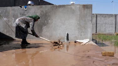 A woman cleans the courtyard of her house after floods in Herat. AFP