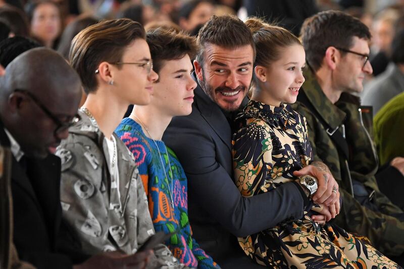 TOPSHOT - Sons of David and Victoria Beckham, Romeo Beckham (2nd L) and Cruz Beckham (3rd L), David Beckham (C) and his daughter Harper (2nd R) take their seats in the front row for the catwalk show by fashion house Victoria Beckham during their Autumn/Winter 2020 collection on the third day of London Fashion Week in London on February 16, 2020.  / AFP / DANIEL LEAL-OLIVAS
