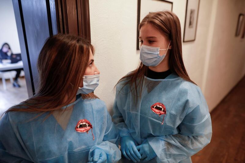 Medical workers, wearing protective gowns decorated with bloody vampire mouth stickers, wait for patients at the temporary Covid-19 vaccination centre at Bran Castle. Reuters