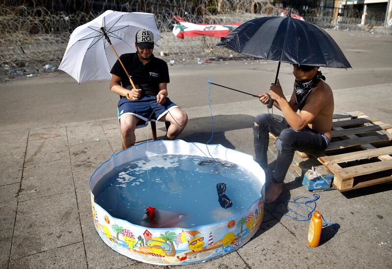 Anti-government protesters stage a satirical installation of how polluted Lebanon's seas are, by fishing in a trash-filled children's swimming pool, in front of the government palace in Beirut, Lebanon. AP Photo