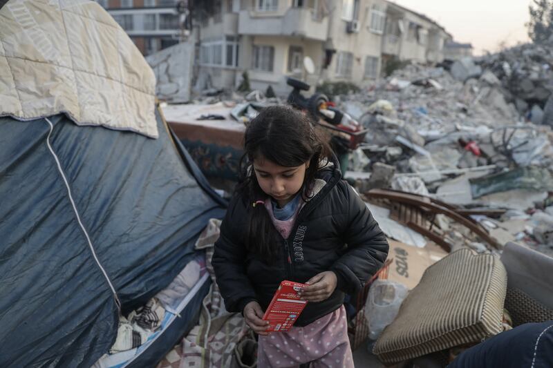 A girl walks near a tent beside collapsed buildings on Monday in Hatay, Turkey. Getty