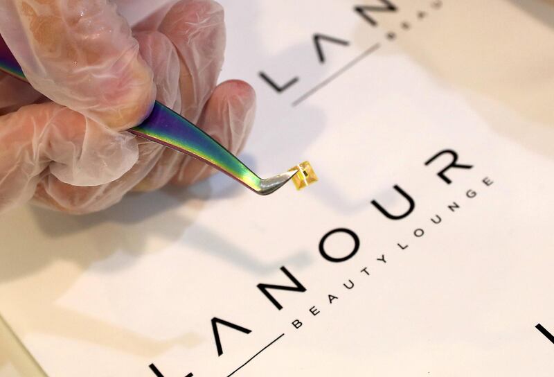 Staff pasting the microchip on the nail at the Lanour Beauty Lounge in Duja tower in Dubai on June 22,2021. Lanour Beauty Lounge in Dubai is offering microchip manicures, which paint a microchip which can double as a business card under the nail. The idea came about as a covid-friendly way of sharing business cards. Pawan Singh / The National. Story by Gill