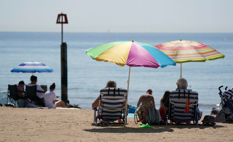 People sit under a sun shade on the beach in Bournemouth, southern England. The mercury could climb as high as 33°C over the next few days.