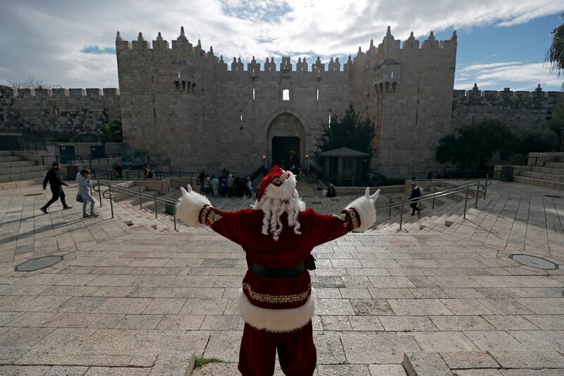 Issa Kassissieh, dressed as Santa Claus, greets people at the Damascus gate of the Old City of Jerusalem as part of Christmas preparations. EPA
